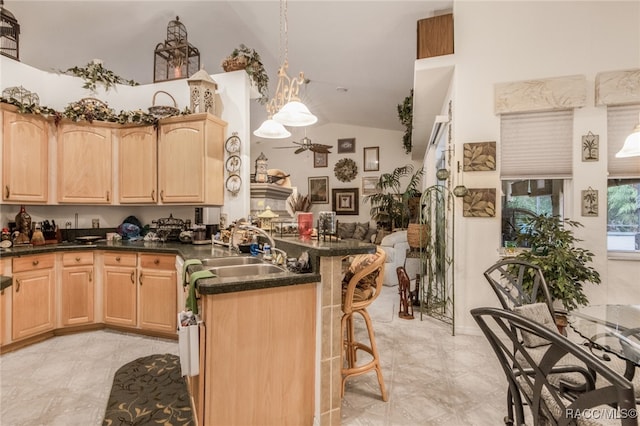 kitchen featuring a breakfast bar, ceiling fan, sink, and light brown cabinetry