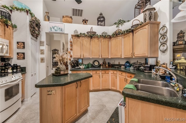 kitchen with light brown cabinetry, a center island, white gas stove, and sink