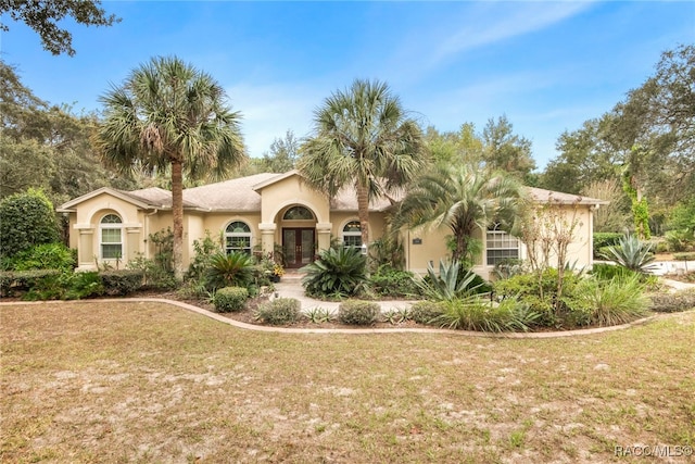 mediterranean / spanish-style house with french doors and a front lawn