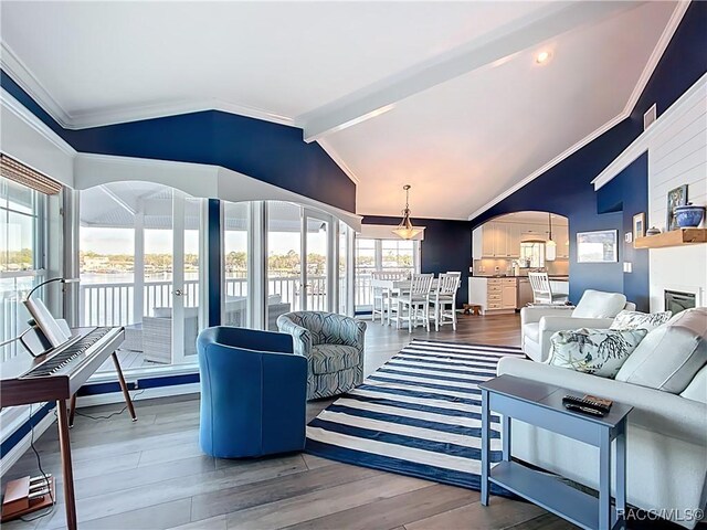 living room with wood finished floors, lofted ceiling with beams, a fireplace, arched walkways, and crown molding