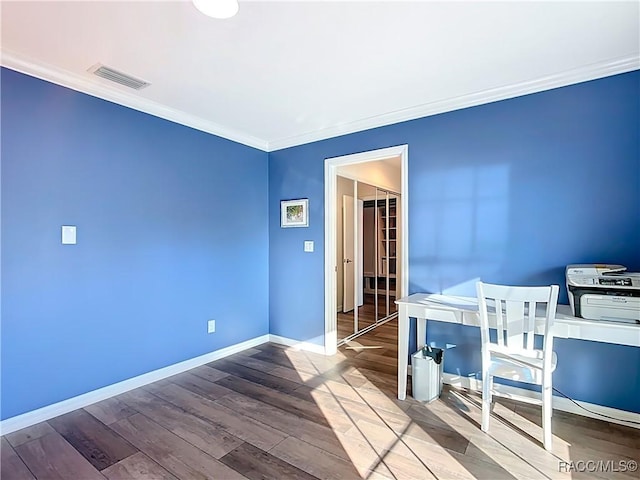 bedroom with visible vents, wood finished floors, baseboards, and ornamental molding