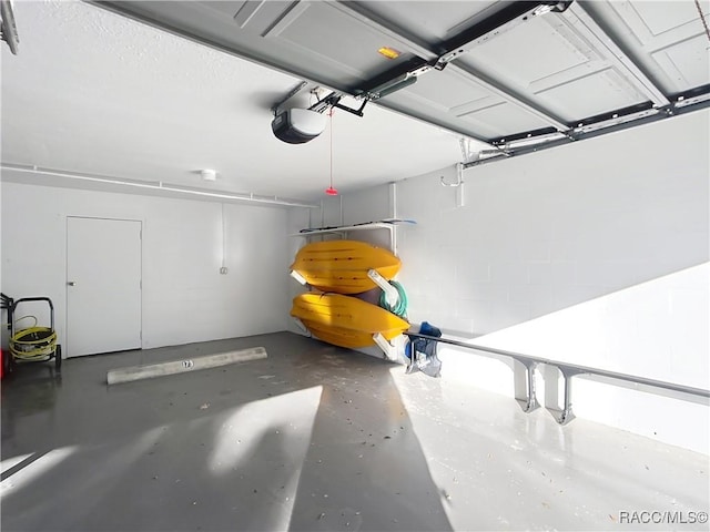 garage with a garage door opener and concrete block wall