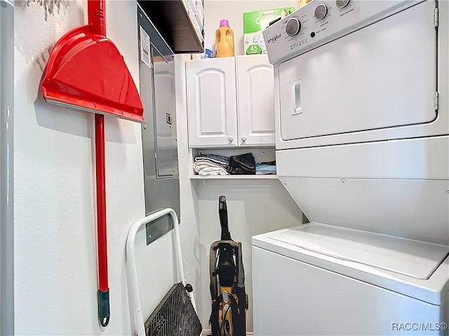 washroom with cabinet space and stacked washer / drying machine