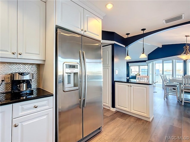 kitchen with visible vents, stainless steel fridge, dark countertops, and vaulted ceiling