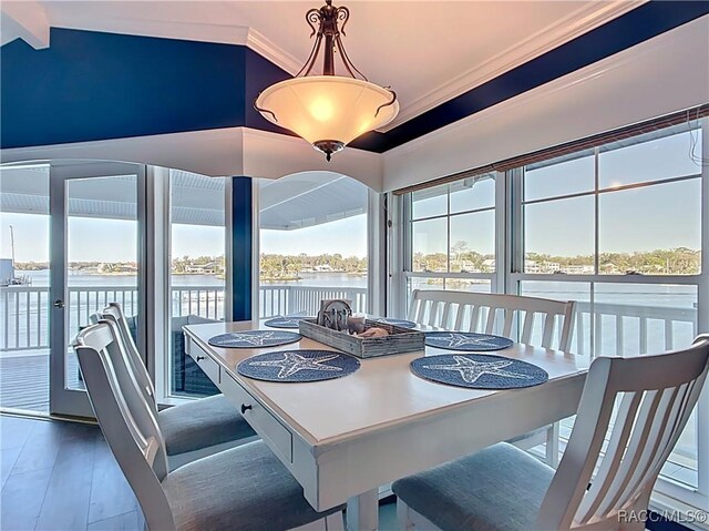 dining area featuring a water view, plenty of natural light, wood finished floors, and vaulted ceiling with beams