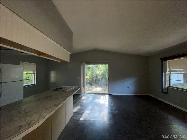 kitchen with plenty of natural light, white refrigerator, and lofted ceiling