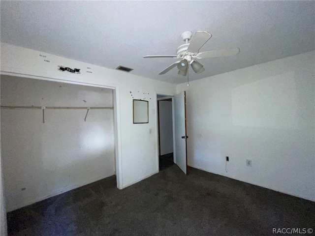 unfurnished bedroom with dark colored carpet, a closet, and ceiling fan