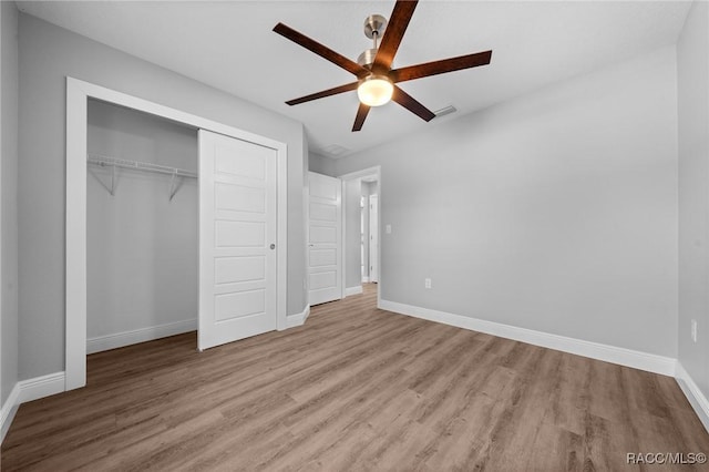 unfurnished bedroom featuring light wood-type flooring, ceiling fan, and a closet