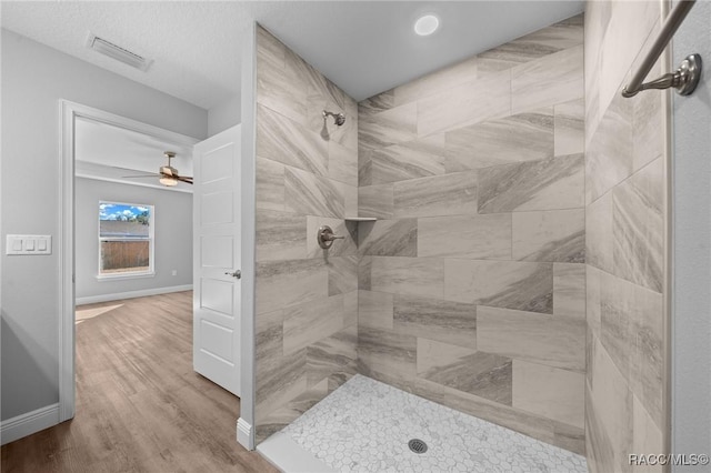 bathroom featuring ceiling fan, hardwood / wood-style flooring, and tiled shower