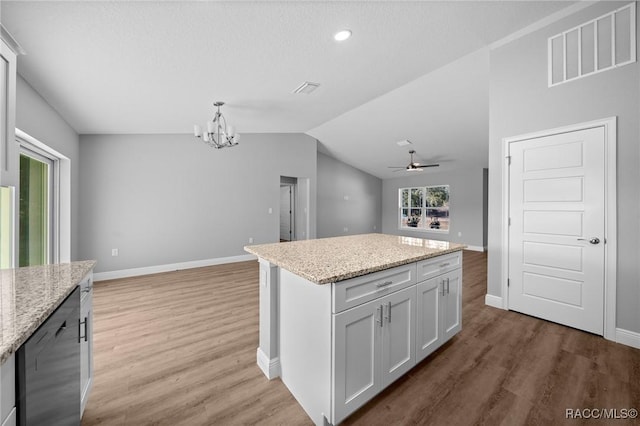 kitchen featuring hanging light fixtures, white cabinetry, light stone countertops, and a center island