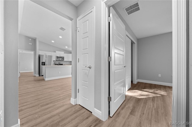 hall with lofted ceiling and light hardwood / wood-style floors