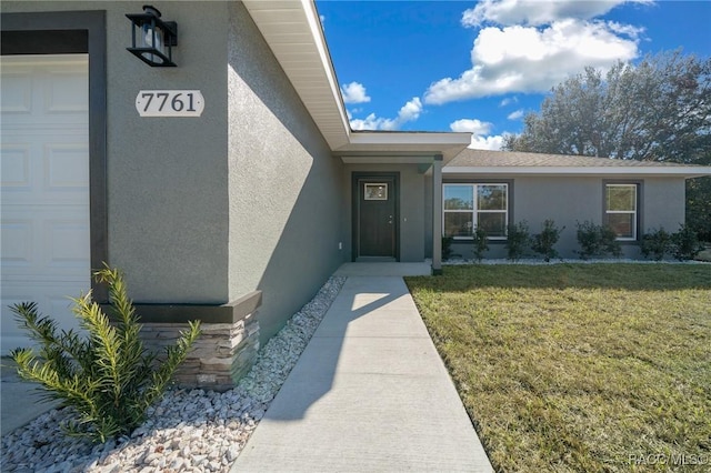 property entrance featuring a garage and a lawn