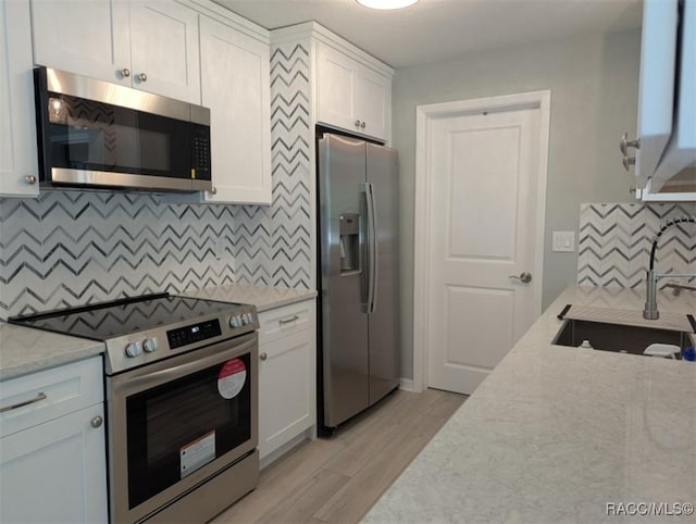 11 N Jefferson St, Beverly Hills, FL 34465 - kitchen featuring stainless steel appliances, tasteful backsplash, white cabinets, and light wood-style floors