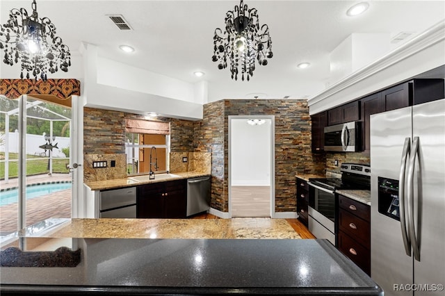 kitchen with an inviting chandelier, appliances with stainless steel finishes, decorative light fixtures, dark brown cabinets, and sink