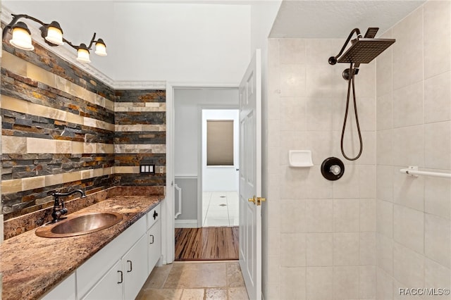 bathroom with a tile shower and vanity