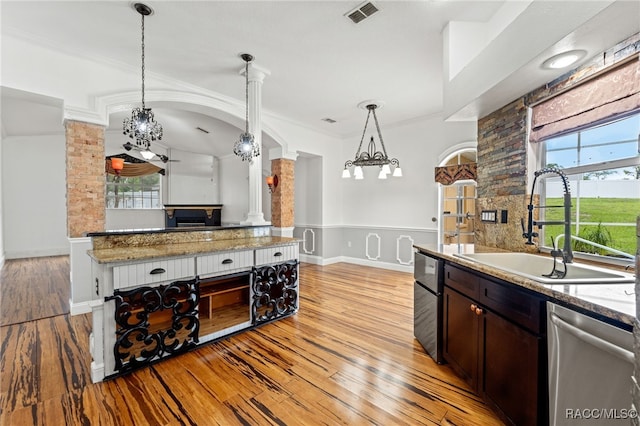 kitchen with decorative light fixtures, ornate columns, light hardwood / wood-style floors, sink, and ornamental molding