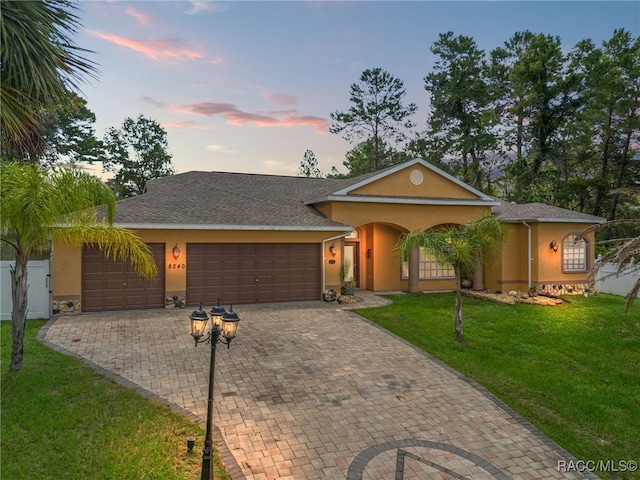 ranch-style home featuring a garage and a lawn