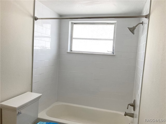 bathroom featuring tiled shower / bath combo and toilet