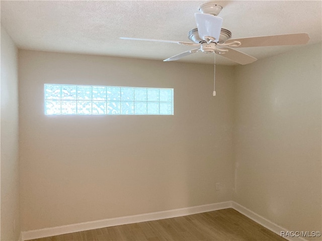 unfurnished room with a wealth of natural light, ceiling fan, wood-type flooring, and a textured ceiling