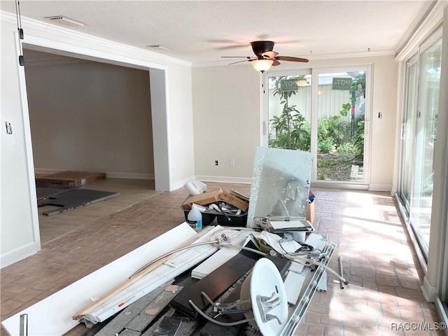 living room featuring ceiling fan, a healthy amount of sunlight, ornamental molding, and a textured ceiling