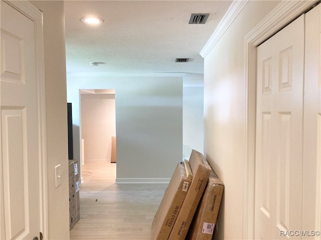 corridor featuring a textured ceiling, light hardwood / wood-style floors, and crown molding