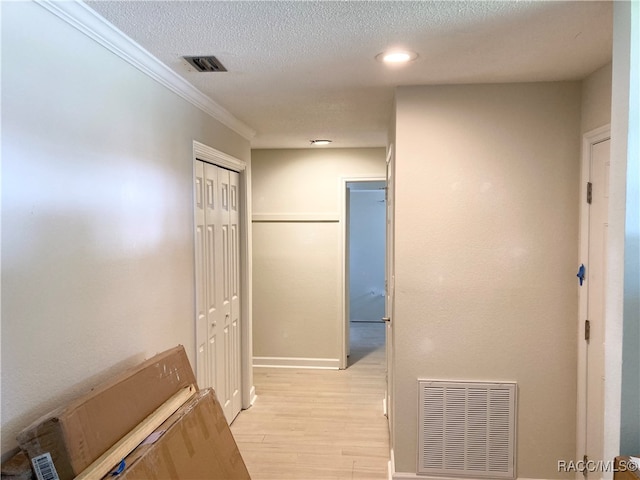 hallway with light hardwood / wood-style floors, a textured ceiling, and ornamental molding