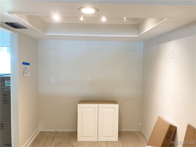 empty room featuring a tray ceiling and light hardwood / wood-style flooring