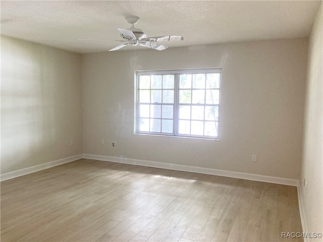 unfurnished room with ceiling fan, light wood-type flooring, and a textured ceiling