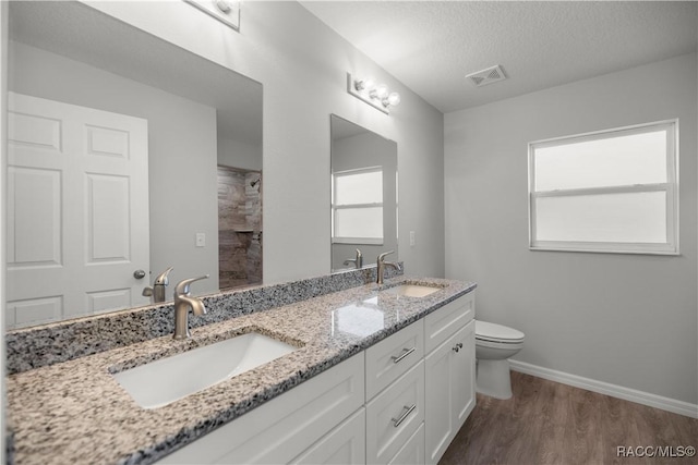 bathroom featuring toilet, vanity, walk in shower, wood-type flooring, and a textured ceiling