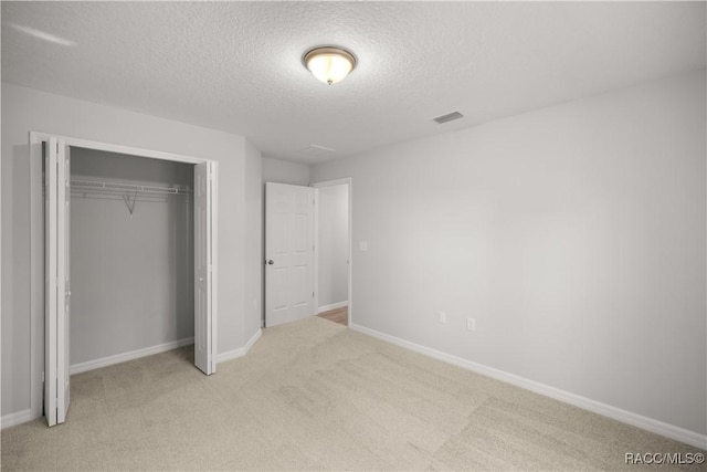 unfurnished bedroom featuring light carpet, a closet, and a textured ceiling