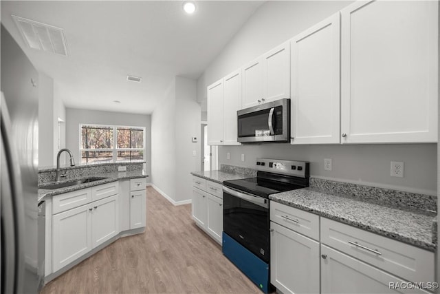 kitchen featuring appliances with stainless steel finishes, white cabinetry, light stone counters, and sink