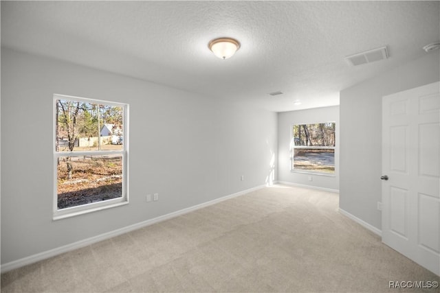 empty room with light carpet and a textured ceiling