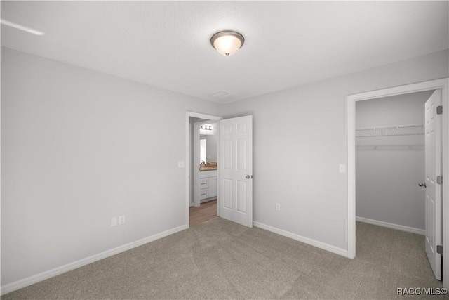 unfurnished bedroom with light colored carpet, a closet, and a spacious closet