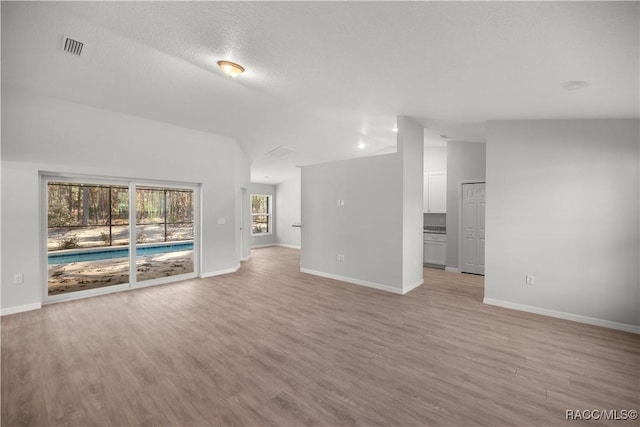 unfurnished living room with a textured ceiling and light hardwood / wood-style flooring