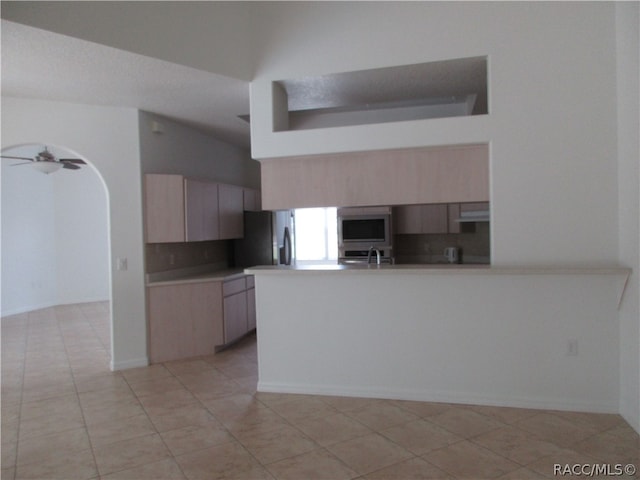 kitchen featuring kitchen peninsula, decorative backsplash, stainless steel appliances, and light tile patterned floors