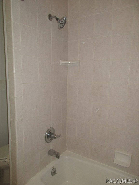 bathroom featuring tiled shower / bath combo and toilet