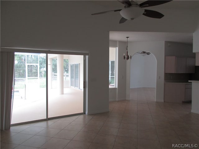 tiled empty room featuring ceiling fan with notable chandelier