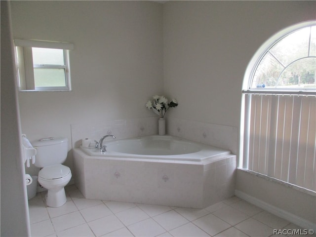 bathroom with tile patterned flooring, toilet, and tiled tub