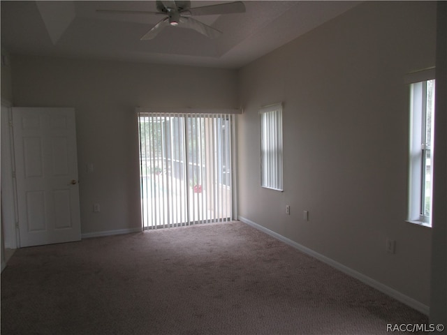 carpeted spare room with a tray ceiling and ceiling fan