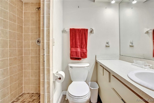 bathroom featuring tiled shower, vanity, and toilet