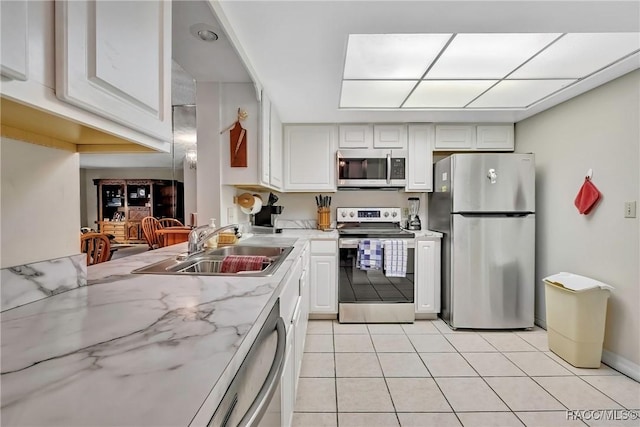 kitchen with sink, stainless steel appliances, white cabinets, and light tile patterned flooring