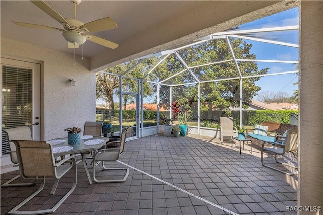 view of patio / terrace with a ceiling fan, a lanai, and fence