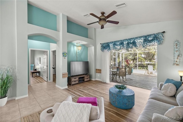 living room featuring visible vents, arched walkways, a ceiling fan, tile patterned floors, and high vaulted ceiling