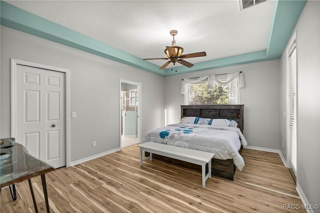 bedroom featuring visible vents, a raised ceiling, and wood finished floors