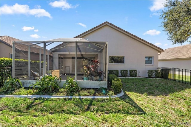 back of property featuring a lanai, fence, a tile roof, a yard, and stucco siding