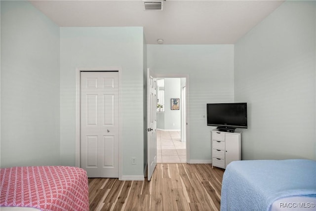 bedroom with baseboards, visible vents, and light wood finished floors