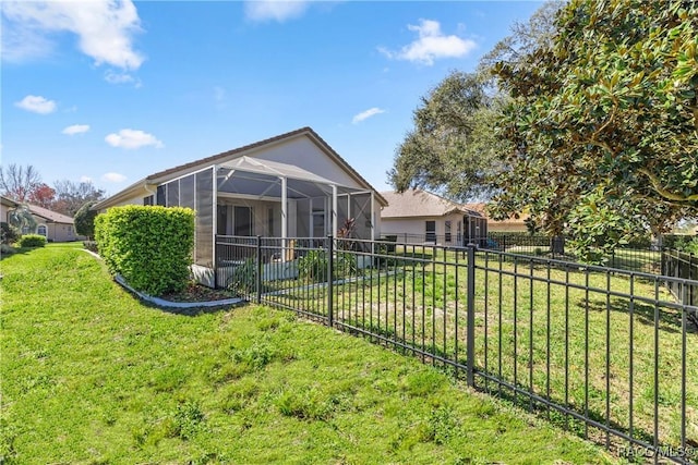 rear view of property with a yard, a fenced backyard, and a lanai