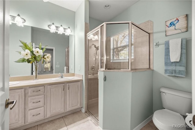 bathroom featuring toilet, a stall shower, a sink, and tile patterned floors