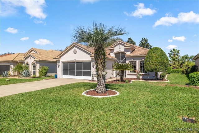 mediterranean / spanish home featuring driveway, a garage, a tiled roof, a front lawn, and stucco siding