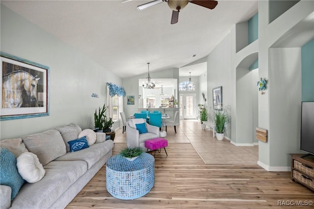 living room featuring arched walkways, high vaulted ceiling, ceiling fan with notable chandelier, baseboards, and light wood finished floors